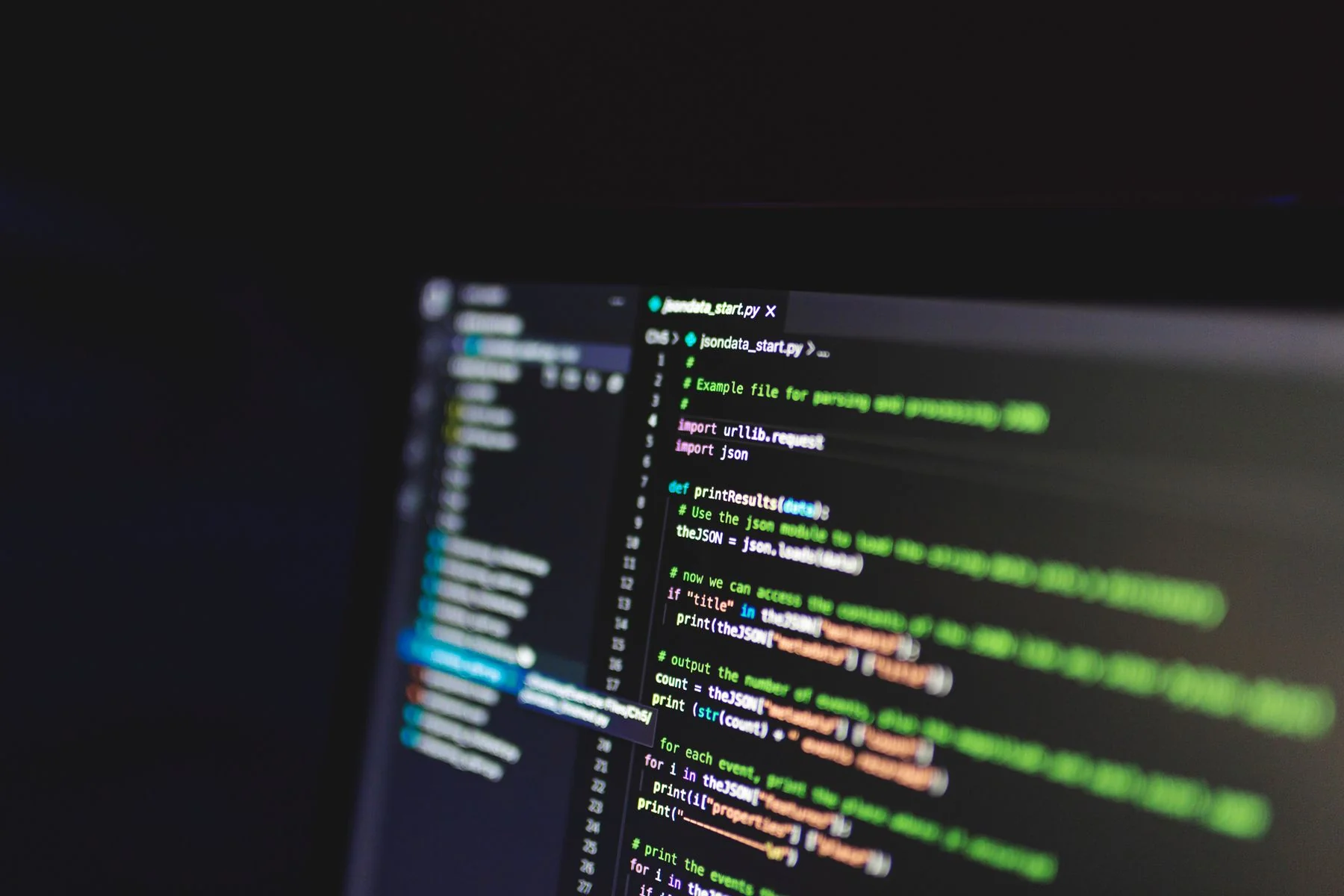 Close-up of colorful programming code on a monitor in a dark room