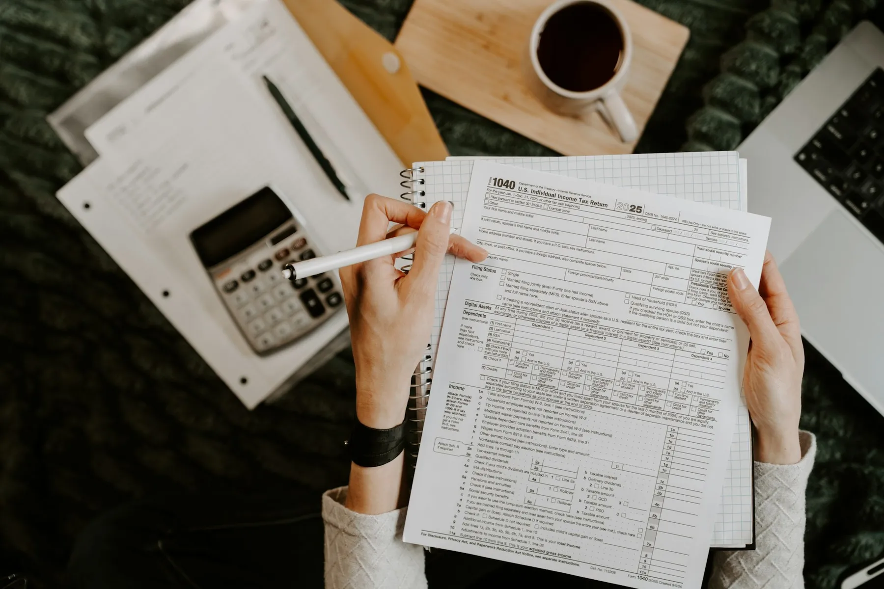 Person reviewing financial documents with a calculator and laptop on a clean desk Person reviewing financial documents with a calculator and laptop on a clean desk